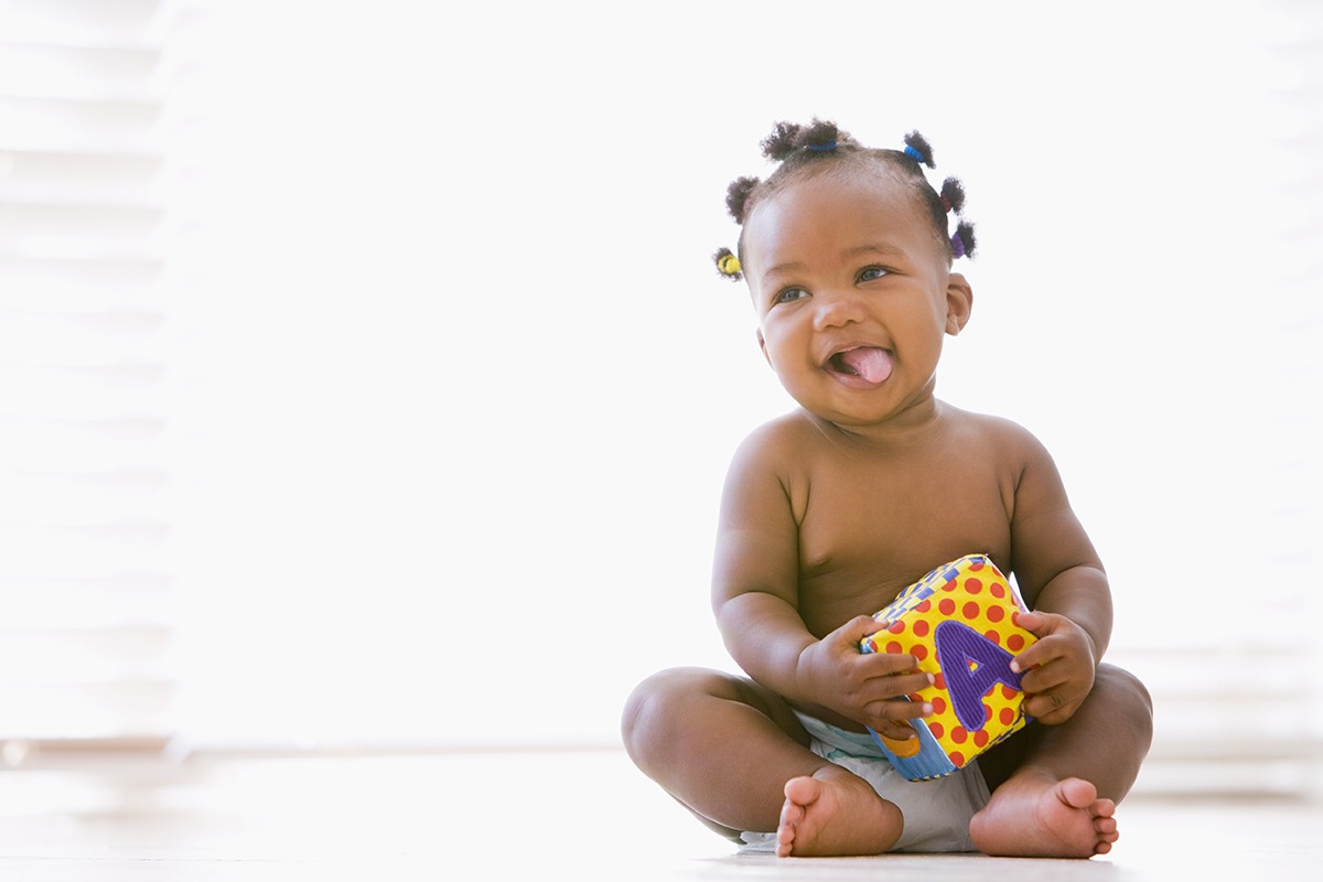 10 month old baby sitting indoors with block smiling sleep