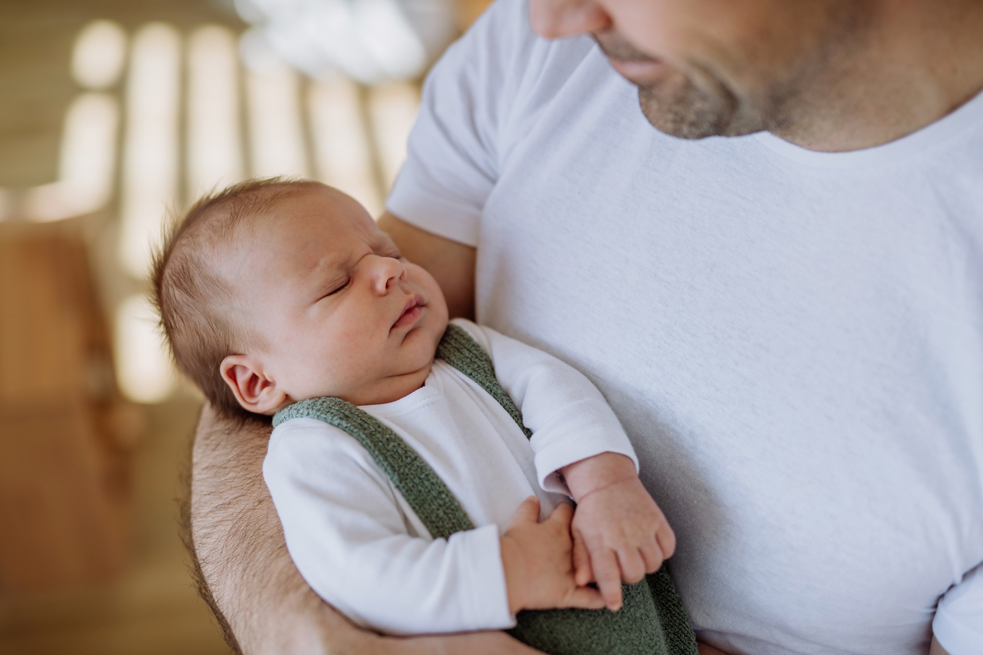 dad holding cute newborn who only wants to sleep in arms